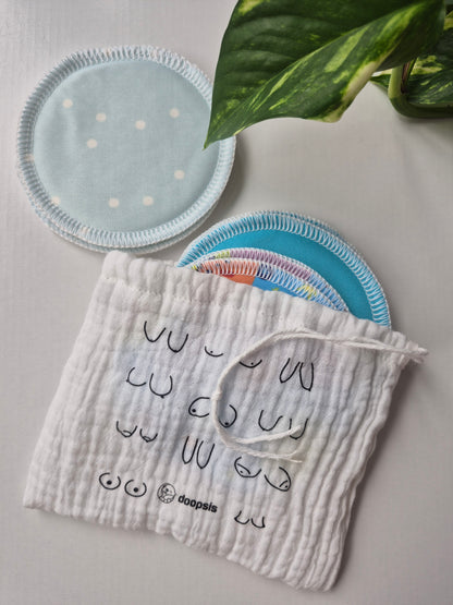 Round fabric item - nursing pad, and rectangular fabric item on a light gray surface with a plant leaf in the corner.