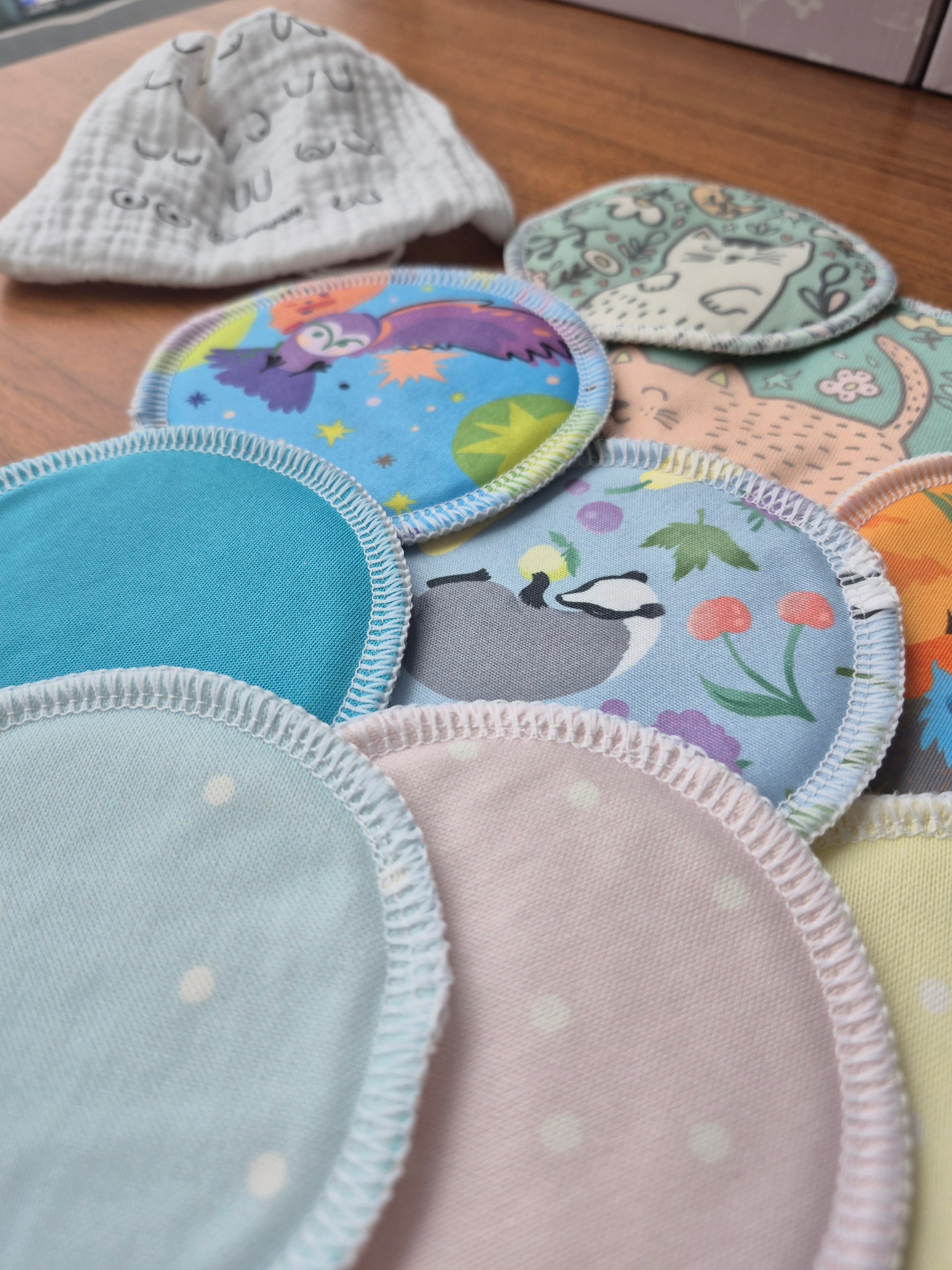 Collection of colorful breast pads with various patterns on a wooden surface.