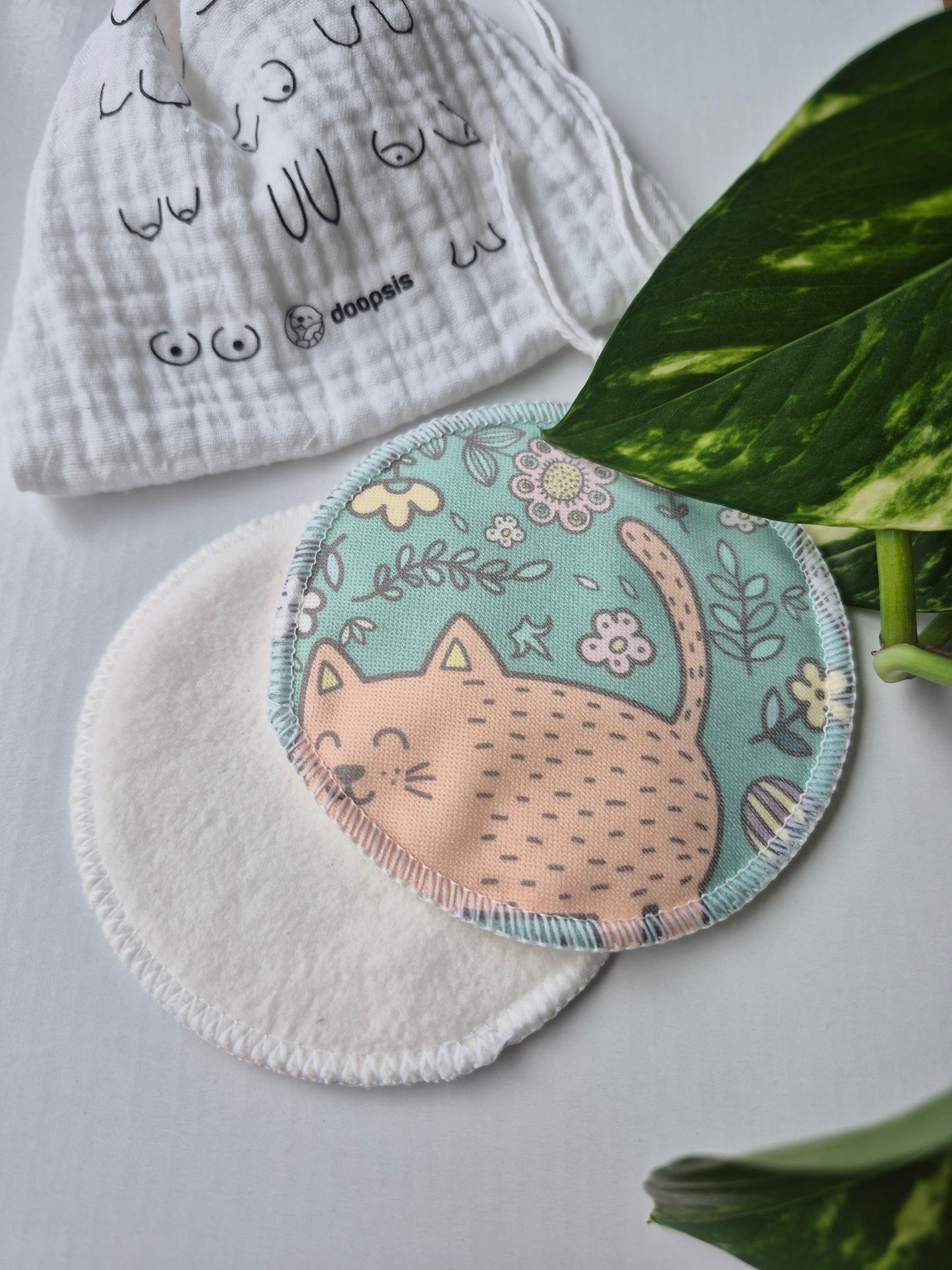 nursing pads with cartoon catdesign on a white surface with green leaves in the background