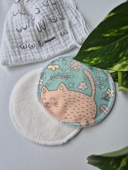 nursing pads with cartoon catdesign on a white surface with green leaves in the background