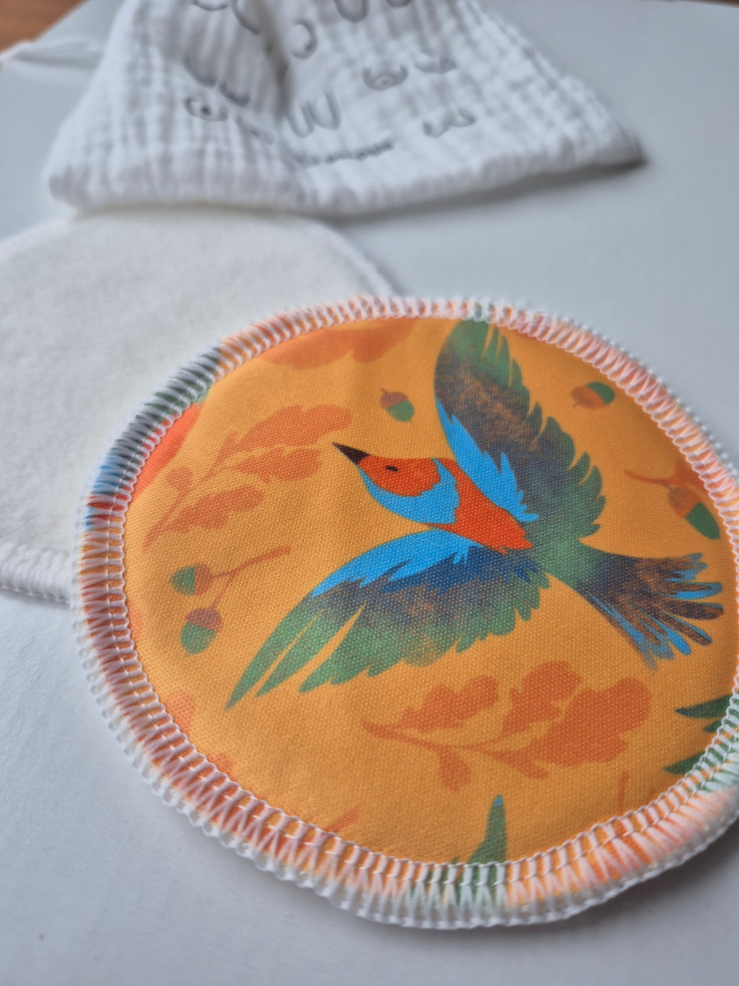 Round nursing pad with a colorful bird design on a white surface