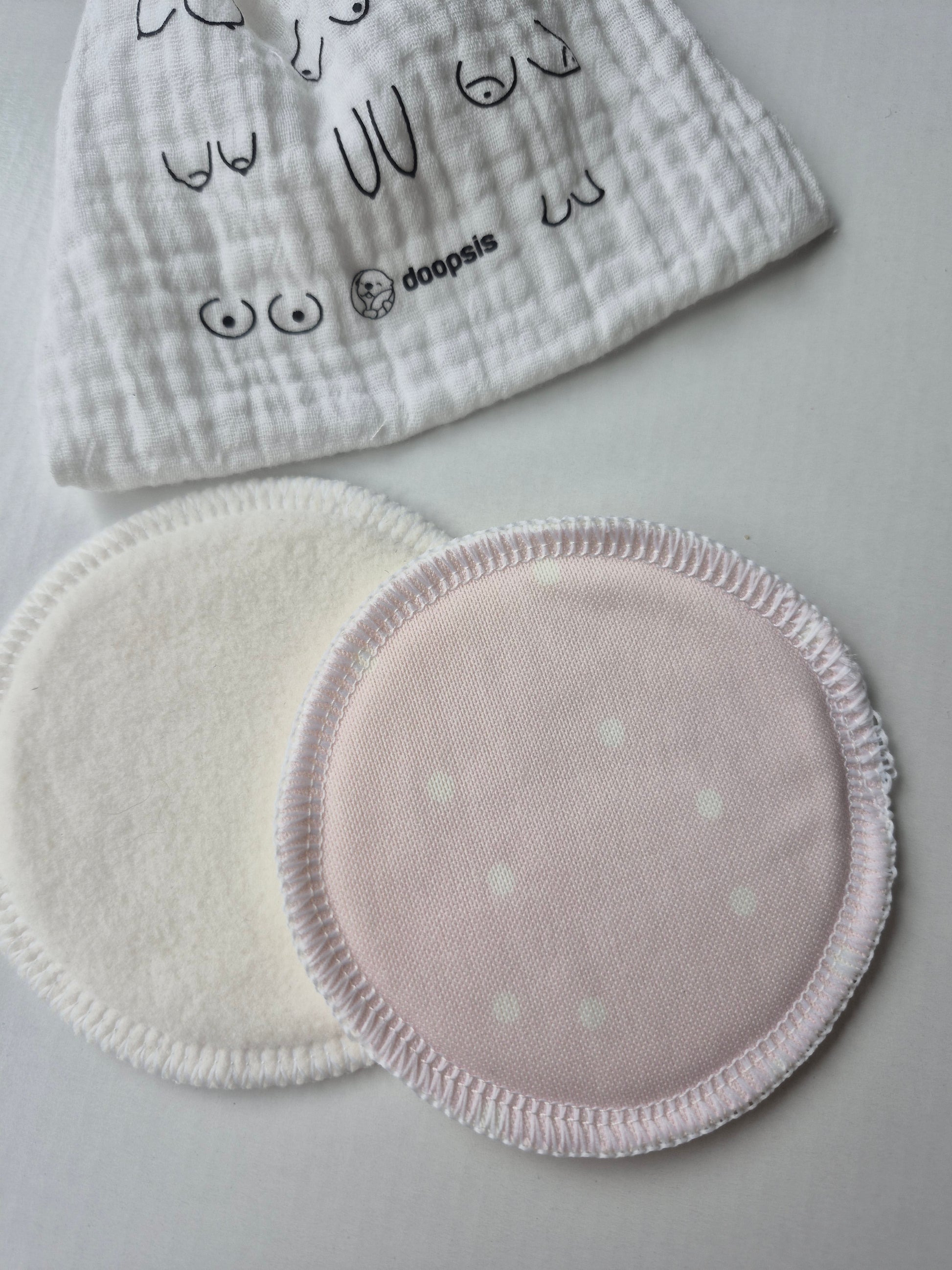 Two circular nursing pads with polka dot pattern on a light gray background