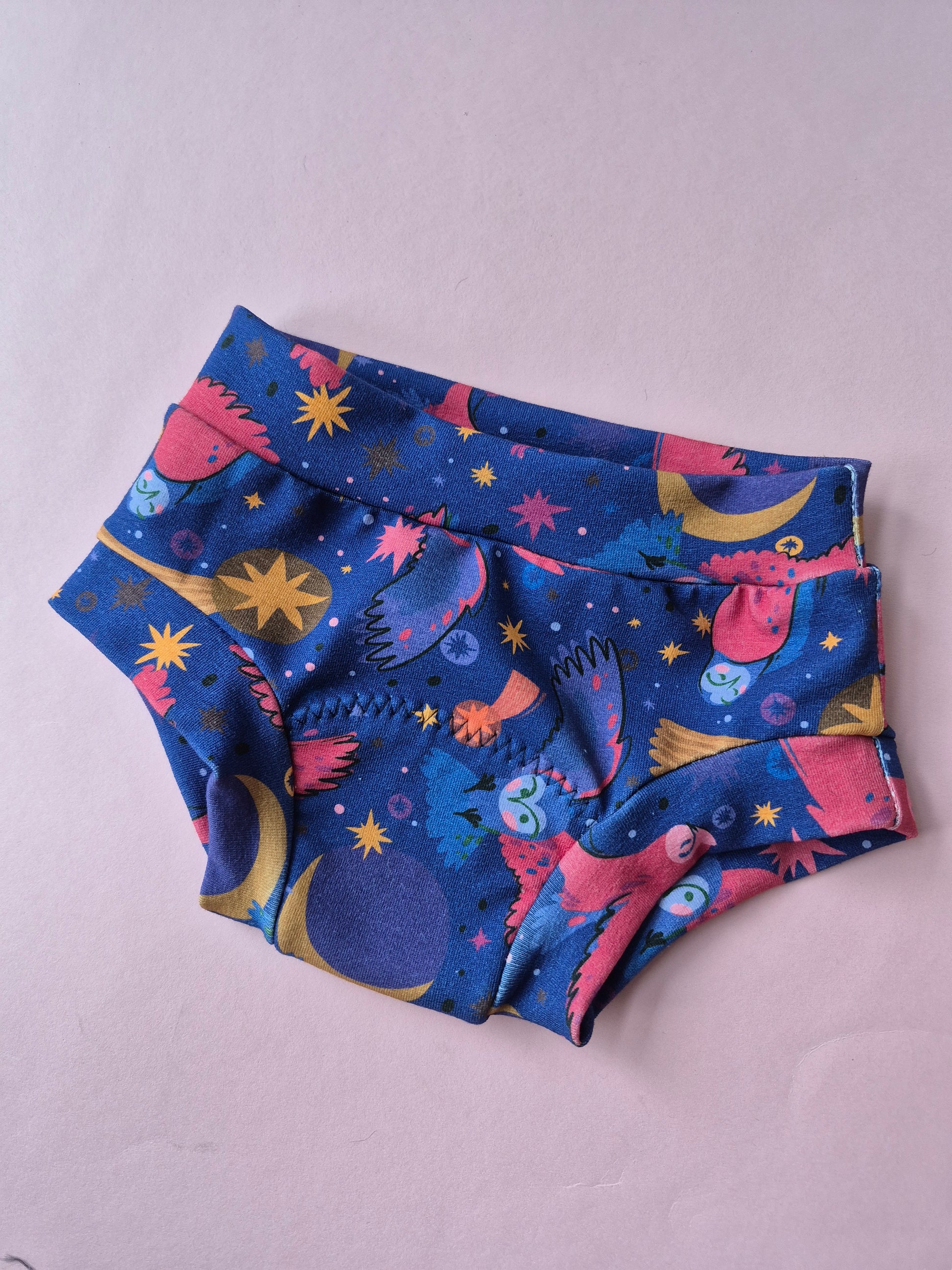 Colorful owl-patterned pottytraining pants on a light pink background