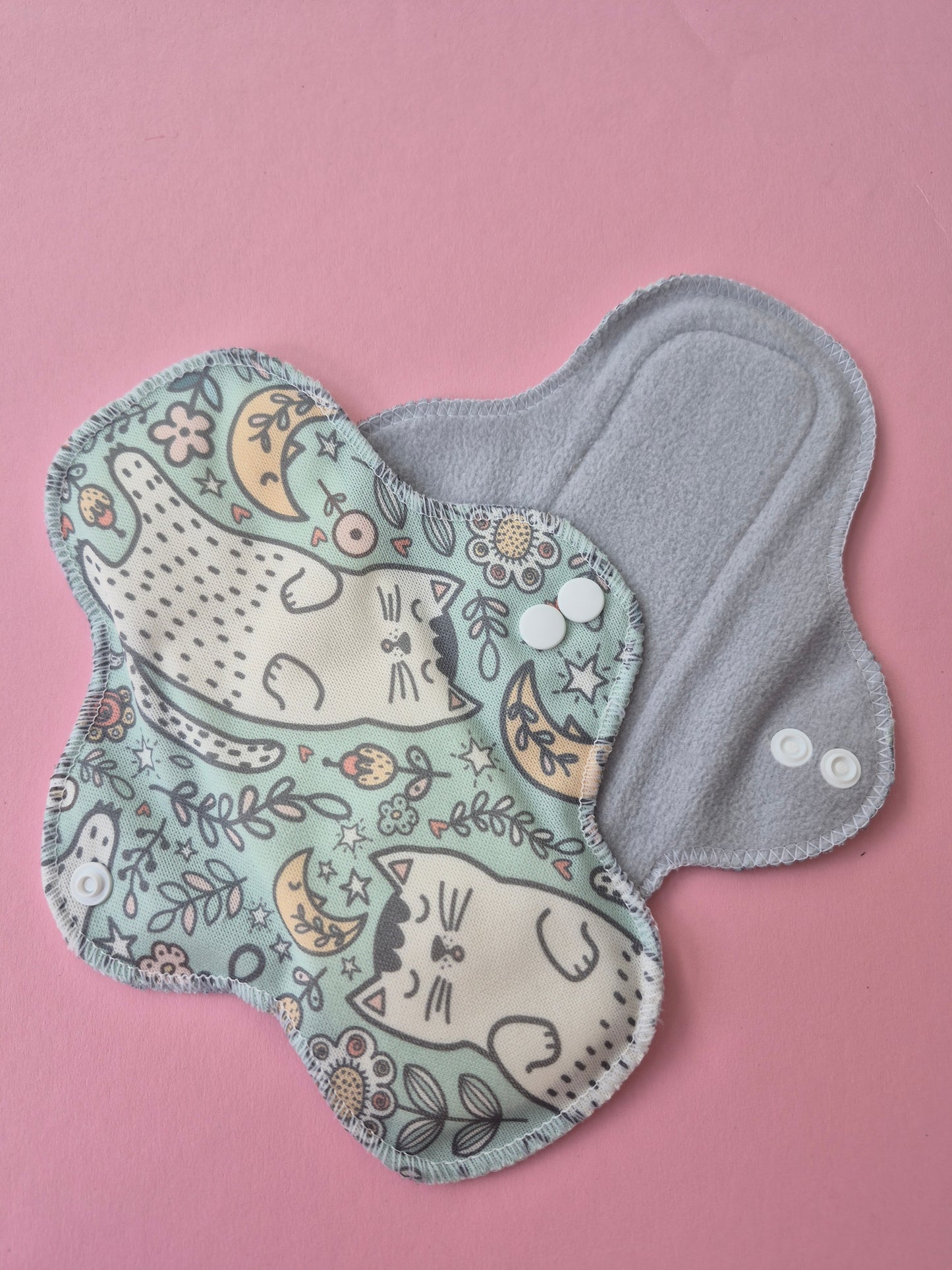 Reusable menstrual pad with cat and moon pattern on a pink background