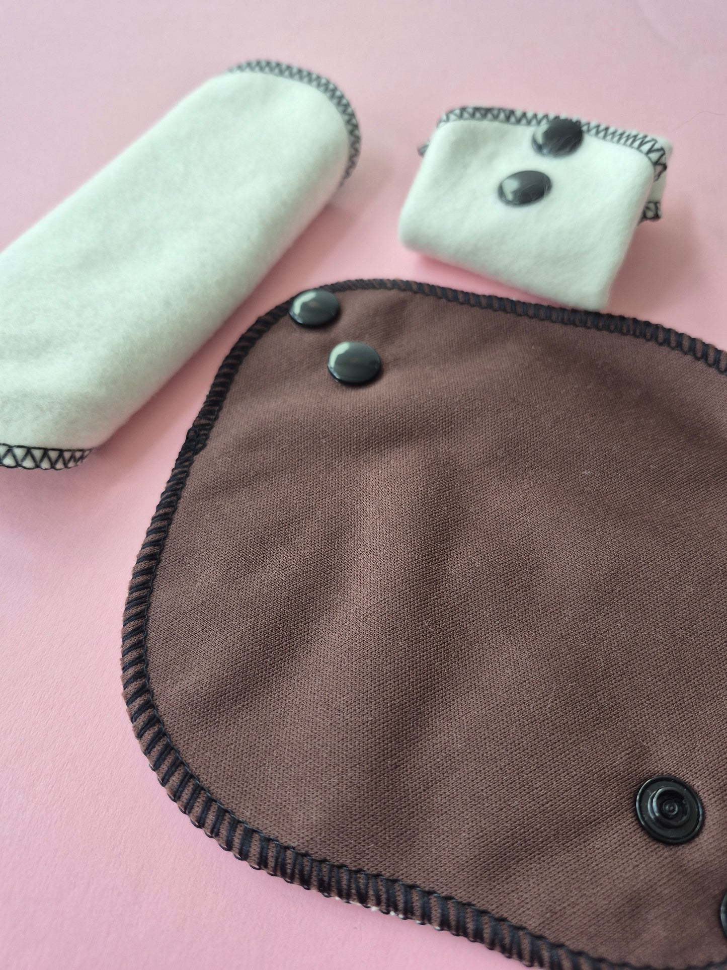 Brown fabric pad with buttons on a pink background