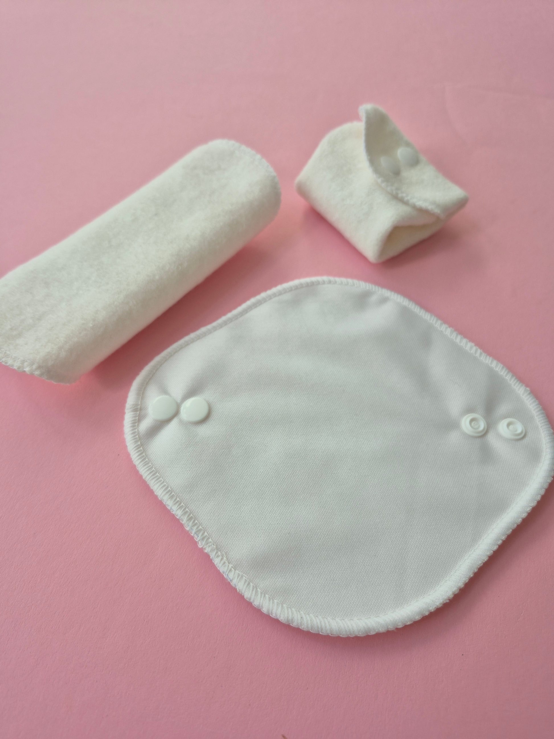 Three pieces of white panty liners on a pink background